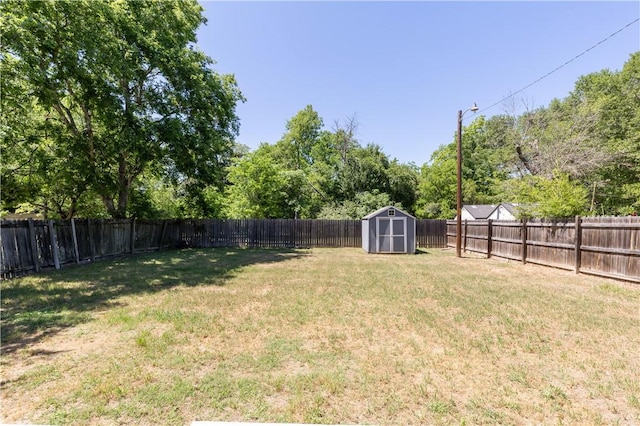 view of yard with an outbuilding, a fenced backyard, and a storage unit