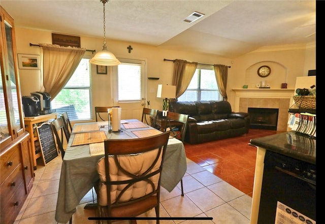 2401 Woodbend Dr, Bryan, TX 77803 - dining space with light tile patterned floors, a tile fireplace, vaulted ceiling, and crown molding
