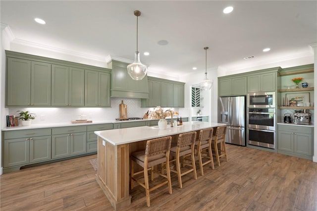 6038 Rain Meadow Dr, College Station, TX 77845 - kitchen with stainless steel appliances, green cabinets, light countertops, decorative light fixtures, and crown molding