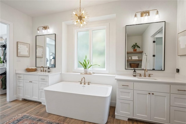 6038 Rain Meadow Dr, College Station, TX 77845 - full bath featuring a chandelier, a freestanding tub, wood finished floors, two vanities, and a walk in closet