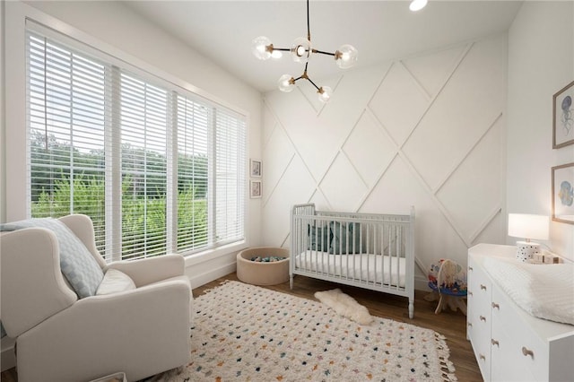 6038 Rain Meadow Dr, College Station, TX 77845 - bedroom featuring a chandelier, wood finished floors, a decorative wall, and a crib