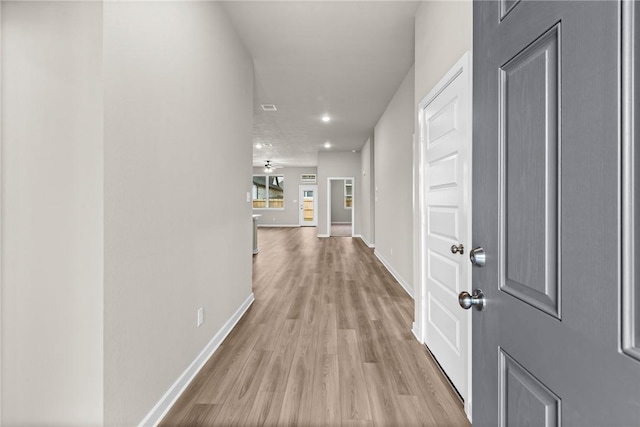 hallway featuring light wood-style flooring and baseboards