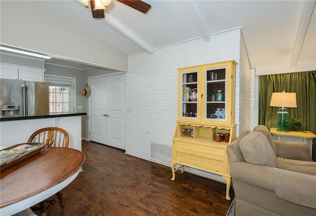 dining room with ceiling fan, dark hardwood / wood-style flooring, brick wall, and lofted ceiling with beams