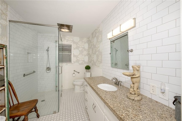 bathroom with tile patterned floors, toilet, tile walls, vanity, and walk in shower