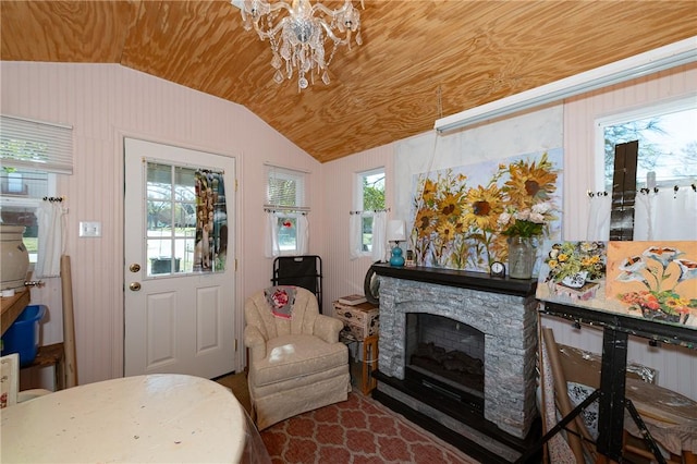 sitting room with lofted ceiling, plenty of natural light, and a stone fireplace