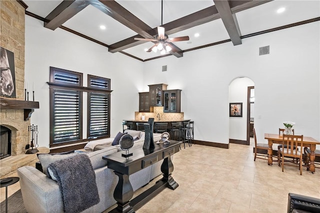 living room with visible vents, baseboards, a fireplace, arched walkways, and a bar