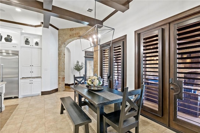 dining room with beamed ceiling, light tile patterned floors, baseboards, and arched walkways