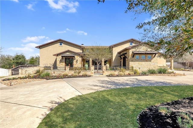 view of front of house featuring a fenced front yard, stone siding, stucco siding, and a front lawn