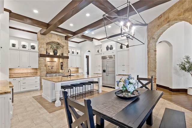 dining room with arched walkways, beamed ceiling, coffered ceiling, and light tile patterned floors