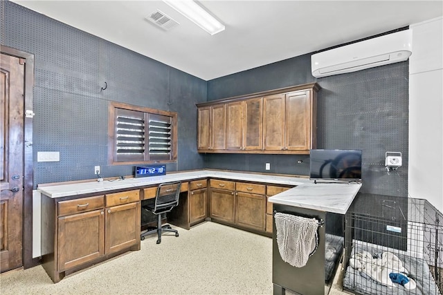 office with visible vents, built in desk, and a wall mounted AC