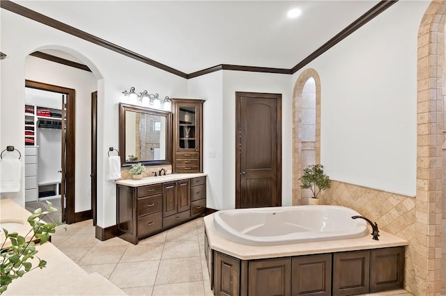 bathroom featuring vanity, a garden tub, a spacious closet, crown molding, and tile patterned floors