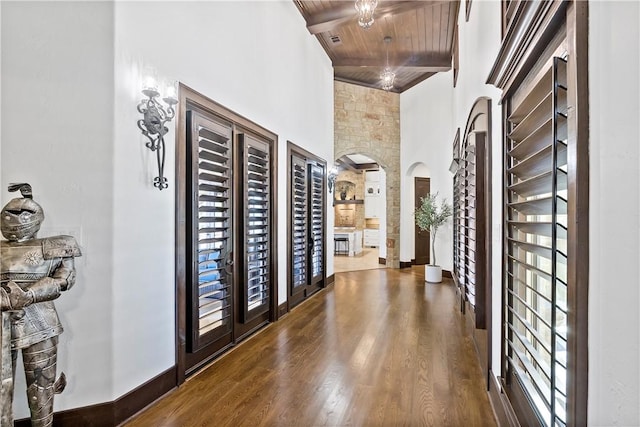 interior space with arched walkways, beamed ceiling, wooden ceiling, and wood finished floors