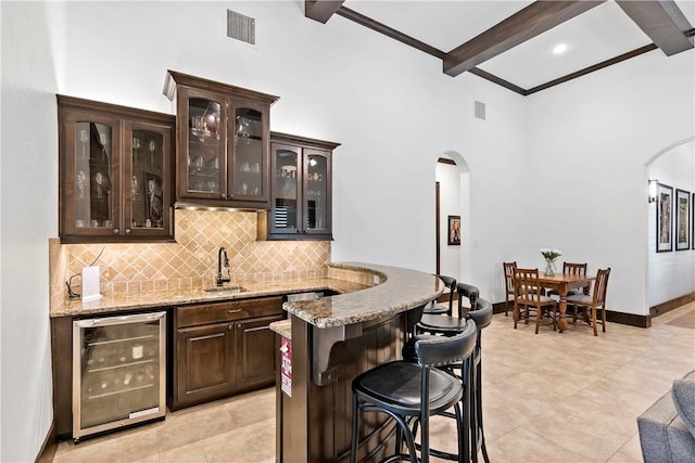 bar with visible vents, wine cooler, arched walkways, and beamed ceiling