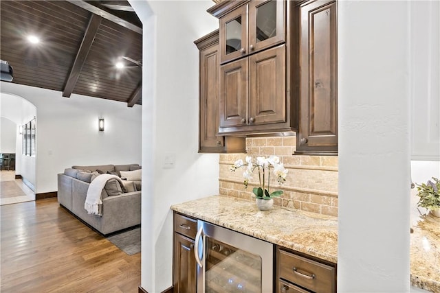 bar with light wood-type flooring, backsplash, wine cooler, arched walkways, and wooden ceiling