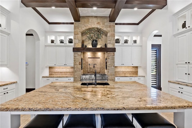 kitchen with a sink, light stone countertops, and backsplash