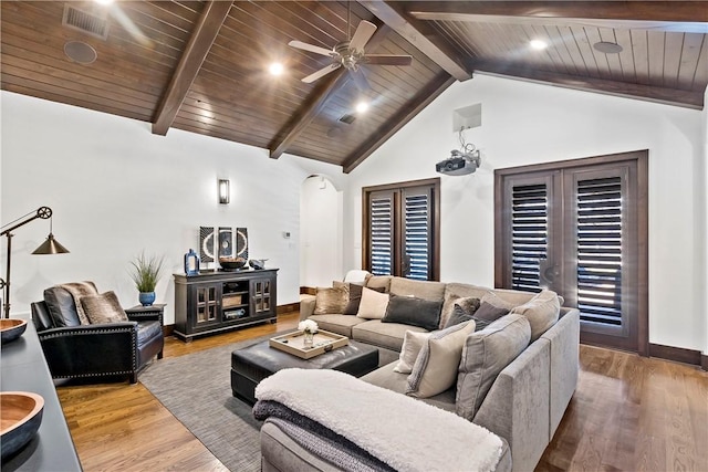 living area featuring beam ceiling, wood finished floors, arched walkways, wooden ceiling, and baseboards