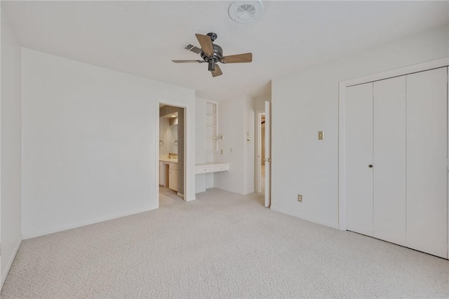 unfurnished bedroom with ensuite bathroom, ceiling fan, light carpet, and a closet