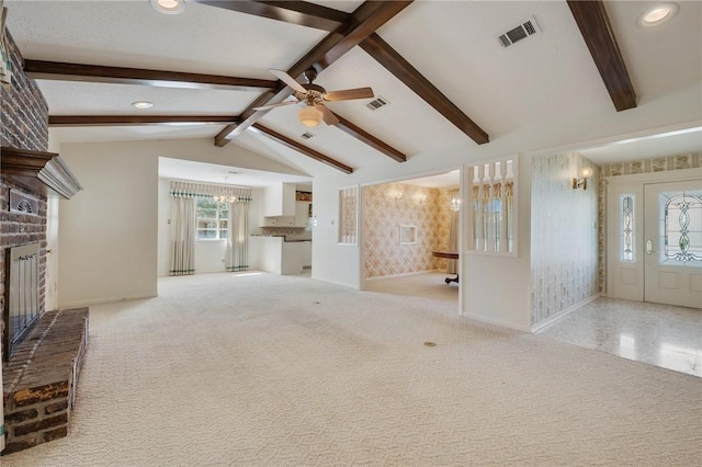 unfurnished living room with vaulted ceiling with beams, light colored carpet, and a fireplace