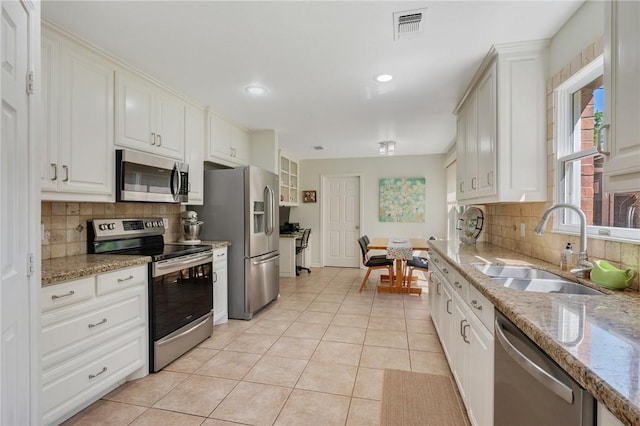 kitchen featuring a sink, stainless steel appliances, light tile patterned floors, tasteful backsplash, and visible vents