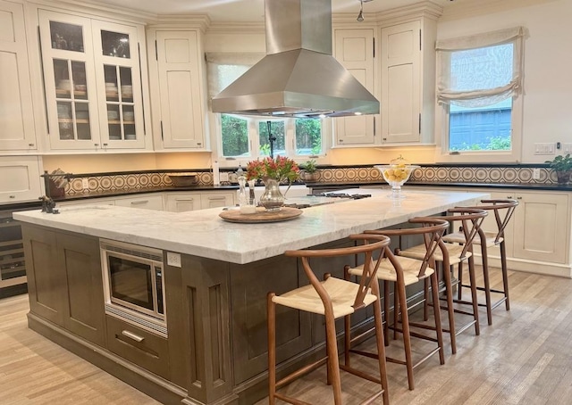 3911 Swarthmore St, Houston, TX 77005 - kitchen with island range hood, stainless steel microwave, a center island, light stone countertops, and ornamental molding