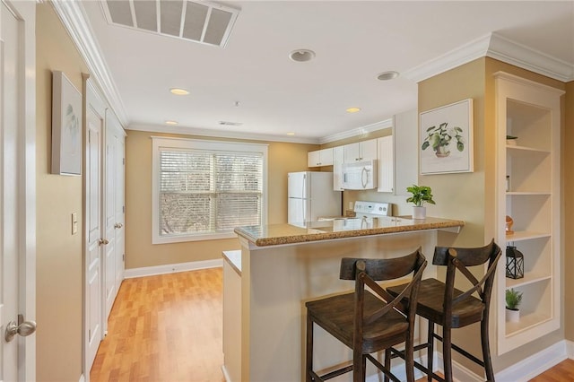 1725 Harvey Mitchell Pkwy, College Station, TX 77840 - kitchen with a kitchen breakfast bar, crown molding, white cabinetry, visible vents, and white appliances