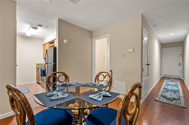 dining room featuring a textured ceiling and light hardwood / wood-style floors