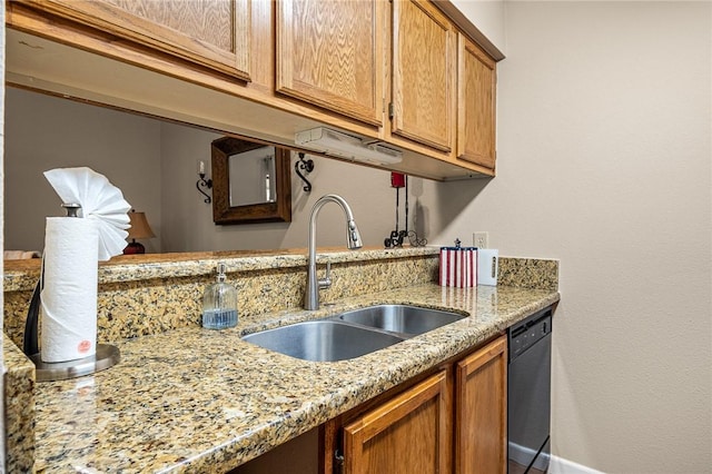 kitchen featuring light stone countertops, sink, and black dishwasher