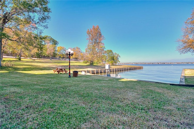 view of dock featuring a water view and a yard