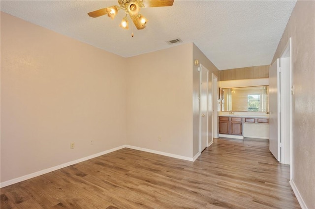 spare room featuring ceiling fan, a textured ceiling, and light hardwood / wood-style flooring