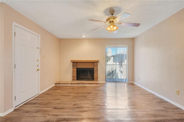 unfurnished living room with a textured ceiling, ceiling fan, wood-type flooring, and a fireplace