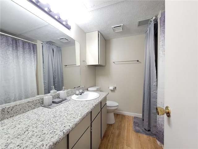 bathroom featuring wood-type flooring, vanity, a textured ceiling, and toilet