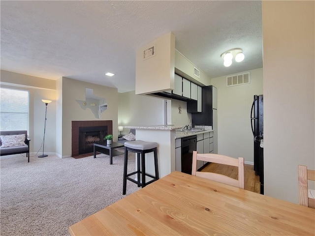 kitchen with a breakfast bar area, a brick fireplace, light carpet, kitchen peninsula, and dishwasher