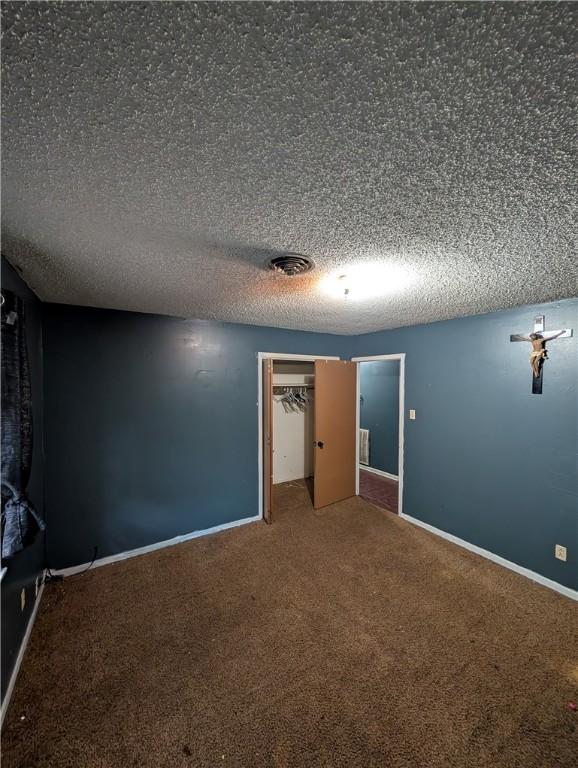 812 Victoria St, Navasota, TX 77868 - unfurnished bedroom featuring carpet flooring, a textured ceiling, and a closet