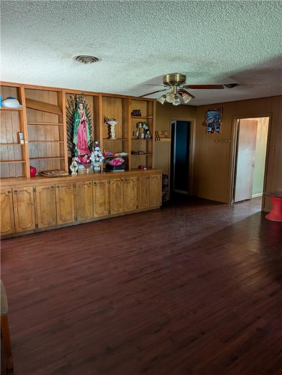 812 Victoria St, Navasota, TX 77868 - unfurnished living room with a textured ceiling, dark wood-type flooring, and a ceiling fan