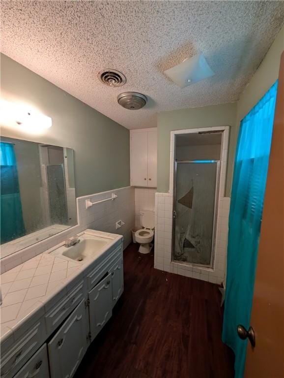 812 Victoria St, Navasota, TX 77868 - bathroom featuring vanity, tile walls, a stall shower, wood finished floors, and a textured ceiling