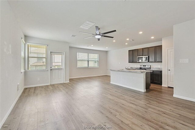 kitchen with a center island with sink, dark brown cabinetry, light wood-type flooring, and stainless steel appliances