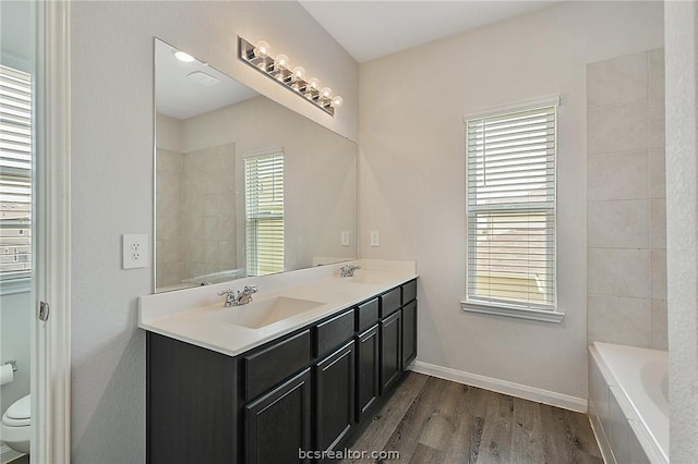 bathroom featuring a washtub, wood-type flooring, vanity, and toilet