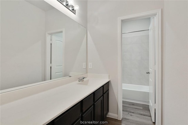 bathroom with tiled shower / bath combo, wood-type flooring, and vanity