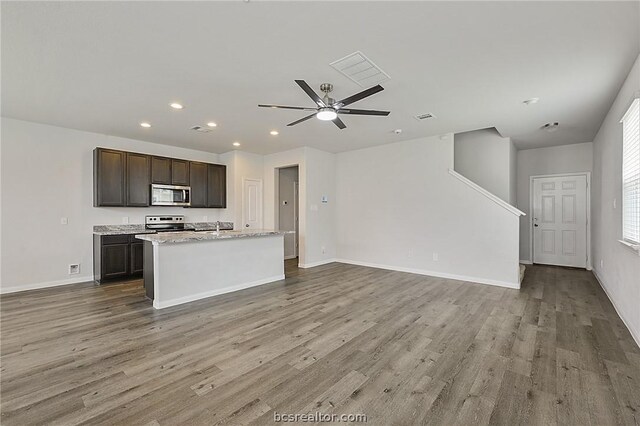 kitchen with light hardwood / wood-style flooring, ceiling fan, an island with sink, appliances with stainless steel finishes, and dark brown cabinetry