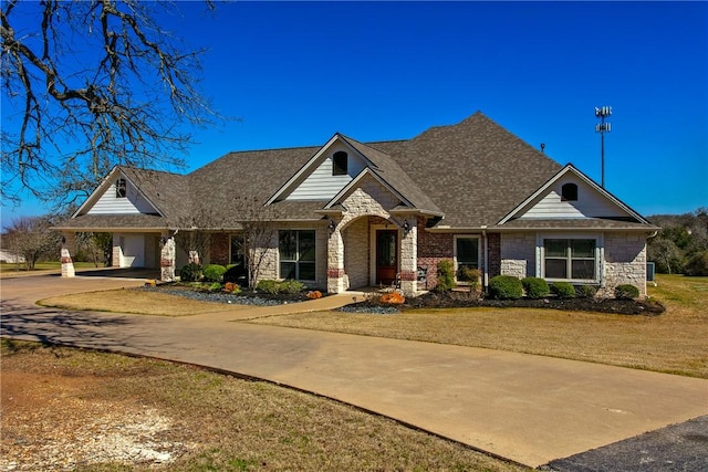 craftsman-style house featuring driveway, stone siding, roof with shingles, and a front yard