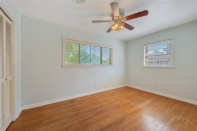 unfurnished bedroom featuring light wood-style flooring, a closet, baseboards, and a ceiling fan