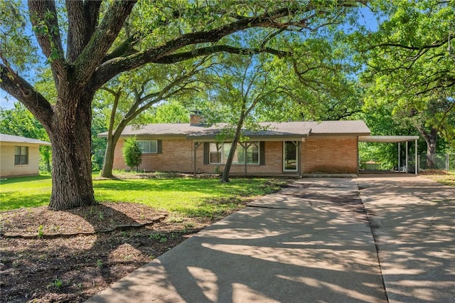 ranch-style home featuring concrete driveway, brick siding, a front yard, and a chimney