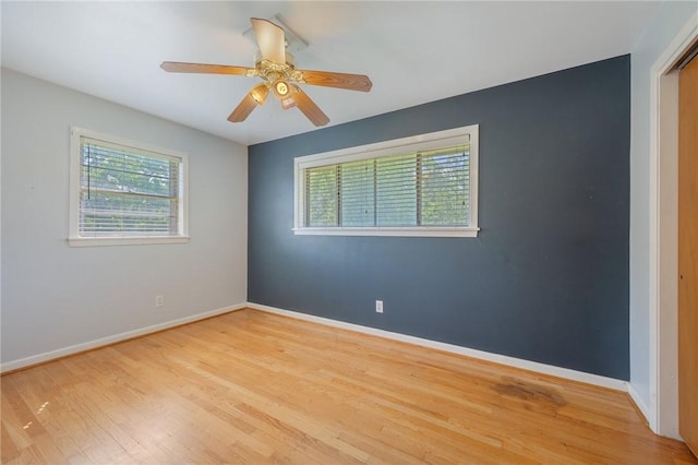 empty room featuring wood finished floors, baseboards, and ceiling fan