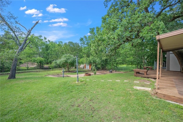 view of grassy yard featuring a deck, an outdoor structure, and a storage unit