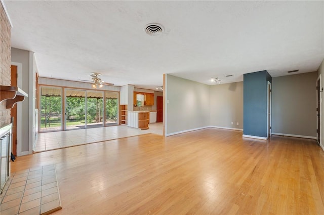 unfurnished living room featuring light wood-style flooring, baseboards, a fireplace, and a ceiling fan