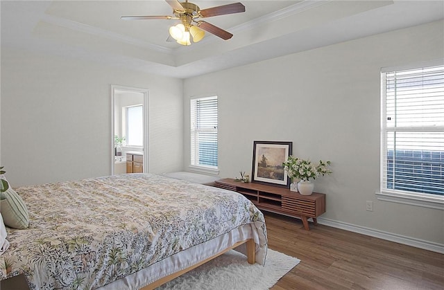 bedroom featuring a raised ceiling, ceiling fan, dark hardwood / wood-style flooring, and multiple windows