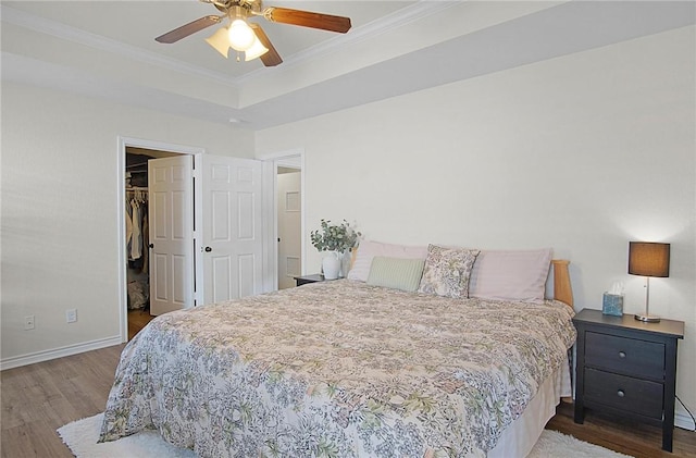 bedroom with ornamental molding, ceiling fan, a spacious closet, dark hardwood / wood-style floors, and a closet