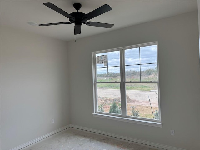 spare room with a ceiling fan, baseboards, and concrete floors