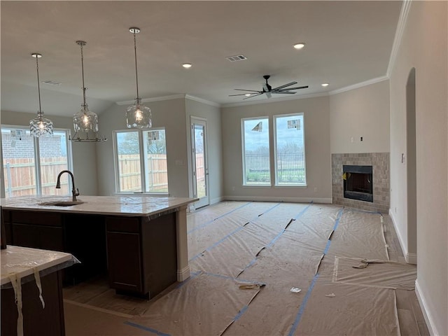 kitchen with visible vents, a sink, open floor plan, crown molding, and baseboards