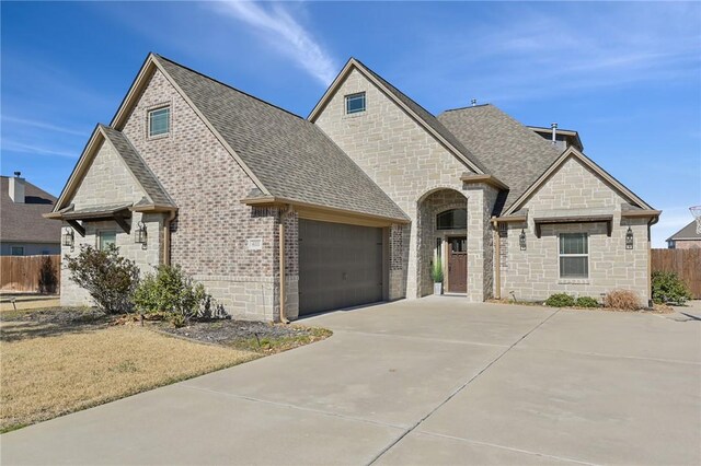4111 Downton Abbey Ave, College Station, TX 77845 - french provincial home with roof with shingles, an attached garage, concrete driveway, and stone siding